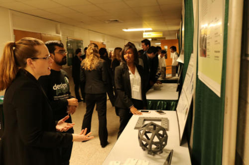 Visitors quiz a Mechanical Engineering student on her team’s project